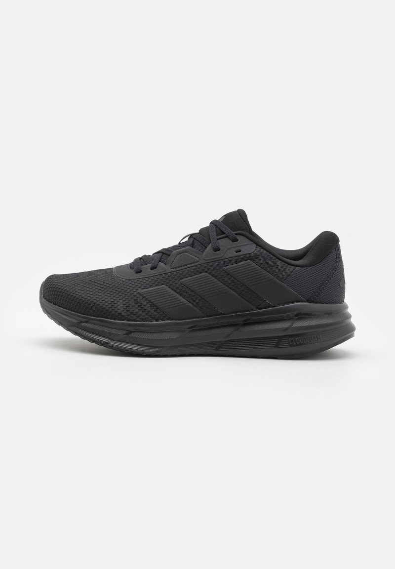 Baskets de sport noires avec tige en mesh, fermeture à lacets et semelle coussinée marquée "Cloudfoam" sur le côté, présentées en profil latéral sur fond blanc.