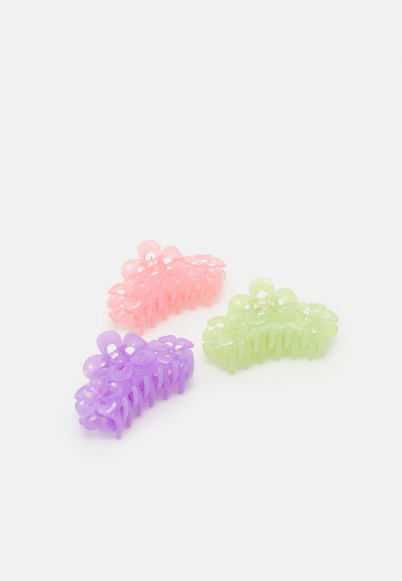 Three plastic hair claws in pastel colors: pink, purple, and green, featuring flower designs with a glossy finish and curved shapes.