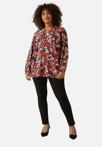 Kukkakuosiset hupparit mustassa, punaisessa ja valkoisessa, jossa on nyöritetty huppu ja pitkät hihat, yhdistettynä mustiin legginsseihin ja korkokenkiin.