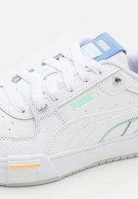 Weiße Leder-Sneaker mit strukturiertem Finish, ergänzt durch türkisfarbene und blaue Akzente, Schnürverschluss und eine Gummisohle mit gelben Details.