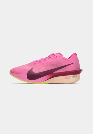 Adidaș roz cu un üst elegant, texturat, mare logo Swoosh de culoare mov, talpă de neon verde și un design distinct al călcâiului cu amortizare.