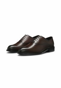 Dark brown polished leather men's dress shoes with closed lacing and slight heel on a white background.