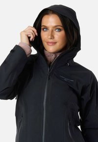 Sort vandtæt jakke med hætte, der har en lynlås foran, sidelommer og justerbar kant. Glat stof med minimalistisk design.