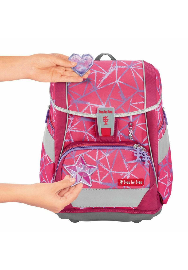 Pink backpack with geometric pattern, grey accents, and two removable purple charms (heart and star). Features silver hardware and zipper.