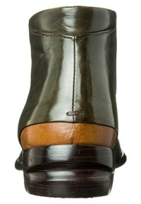 Stivale alla caviglia in pelle verde scuro con tacco impilato in legno e marrone scuro, caratterizzato da una texture liscia e cuciture visibili lungo il retro.