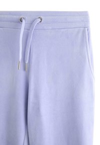 Lyse lilla sweatpants lavet af blødt stof med en snøre med metalender og sidelommer. Teksturen virker glat og børstet.