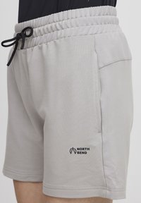 Lysegrå treningsshorts med elastisk midjebånd, snor, sidelomme og svart "NORTH BEND"-logo på venstre ben.
