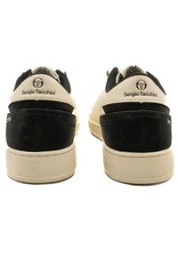 Fekete és krém színű sportcipők sima bőrből és velúrból készült felsőrésszel, kerek orral, vastag talppal és logóval a sarkán.