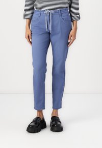 Light blue trousers with a drawstring waist, tapered fit, and front pockets, paired with black platform loafers. Striped top displayed above.