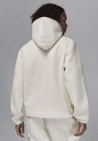 Hvid fleece hættetrøje med en struktureret overflade, der har en rund, pufhue og ribbede manchetter. Blød, varm og afslappet design.