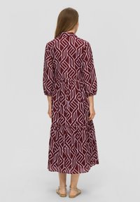 Bordeaux lang jurk met wit geometrisch patroon, elastische taille, driekwart mouwen en gelaagde onderkant. Glad stof, knielang.