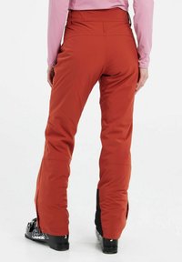 Insulated ski pants in orange with a tailored fit, featuring black accents at the cuffs and zippers at the ankles for adjustable openings.