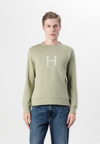 Sudadera de algodón verde claro con cuello y puños de canalé, que presenta un gran logo de "H" y el nombre de la marca "Hackett" debajo.