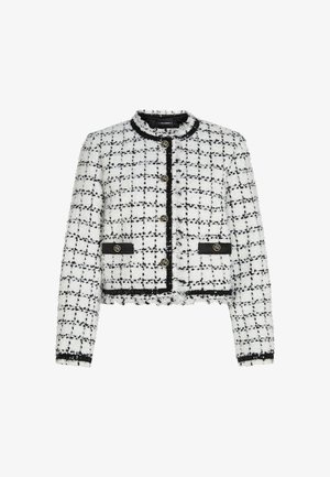 Balta un melna tweed mētelis ar saīsinātu dizainu, apaļu kakla izgriezumu, zelta pogām un melnām akcentiem. Funkcijas ietver plūstošas malas un teksturētu virsmu.