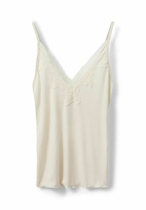 Krämfärgad ribbad camisol med spetskant längs V-ringningen och tunna axelband mot en vit bakgrund.