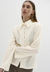 Me�žģīņu pogu krekls off-white krāsā ar vertikāliem svītrām, izteikta uzmava ar garām piedurknēm, vaļēja piegriezuma un pogu aizdari.