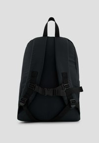 Mochila negra acolchada con correas ajustables anchas, un asa superior y cierre de hebilla. Textura suave con un diseño minimalista.
