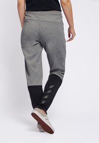 Grijze en zwarte sportjoggingbroeken met een elastische tailleband en een textuurpaneel aan de onderbenen met zwarte chevronaccenten.