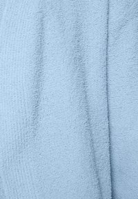 Tessuto azzurro chiaro con superficie morbida e pelosa, caratterizzato da un motivo sottile e una profondità variabile dovuta alle pieghe.