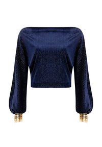 Crop top bleu marine avec une texture brillante, manches bouffantes longues et poignets métalliques dorés. Corps lisse avec des détails en côtes sur les manches.