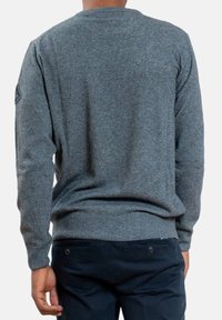 Maglione grigio a maglia con maniche lunghe e scollo rotondo. Presenta una finitura testurizzata e un'etichetta logo sulla manica sinistra.