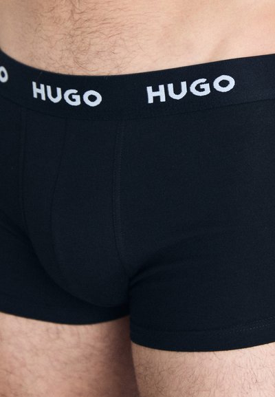 Boxer-briefs noirs en coton avec un ajustement serré, dotés d'une large ceinture élastique avec "HUGO" imprimé en blanc.