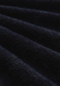 Marineblaues Plüschgewebe mit einer weichen, strukturierten Oberfläche, die vertikale Ripplinien aufweist. Das Licht spiegelt sich subtil von den Fasern wider.