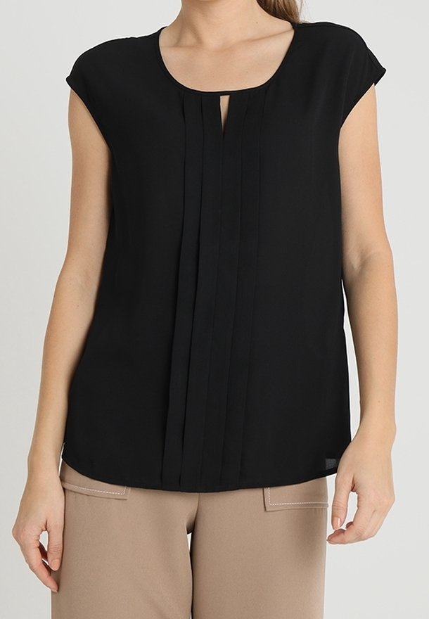 Blusa nera con maniche corte, scollatura rotonda e pieghe verticali sul davanti. Tessuto liscio con una vestibilità comoda. Abbinata a pantaloni beige.