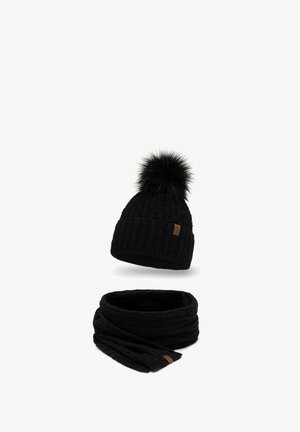 Schwarze Strickmütze mit einem Fell-Pompom und einem passenden schwarzen Strickschal. Verfügt über eine gerippte Textur und ein kleines Logoschild auf jedem Teil.