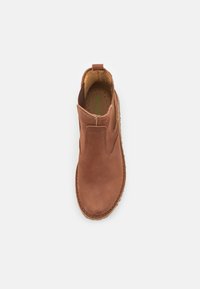 Zapato marrón de piel tipo slip-on con punta redondeada, paneles laterales elásticos y suela texturizada. El interior cuenta con una plantilla perforada.
