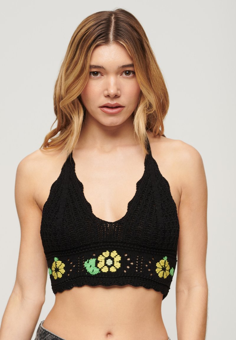 Schwarzes gehäkeltes Bralette mit einem gewellten Ausschnitt, besticktem floralen Muster in Grün und Gelb sowie einem cropped Saum.