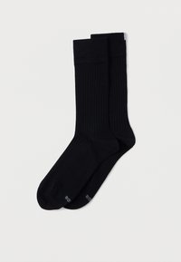 Fekete bordázott zokni, rugalmas anyagból készült. Megerősített orr- és sarokrész jellemzi, az alján finoman nyomtatott logóval.