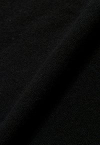 Schwarzer Fleece-Stoff mit weicher Textur, der eine glatte Oberfläche und ein leicht flauschiges Finish aufweist, diagonal gefaltet.