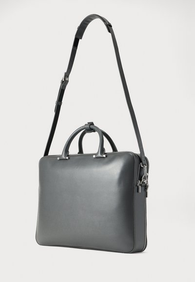 Γκρι δερμάτινη τσάντα για φορητό υπολογιστή με διπλές λαβές και αποσπώμενο ιμάντα ώμου. Ομαλή υφή, ορθογώνιο σχήμα και ασημένιες μεταλλικές λεπτομέρειες.