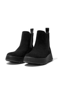 Botas de tobillo de ante negro con paneles laterales elásticos, tiradores y suelas de goma gruesas, que presentan una silueta estilizada y un acabado texturizado.
