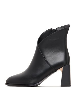 Black leather ankle boot with a pointed toe, angled cut at the upper, and a chunky block heel. Smooth texture with minimal detailing.