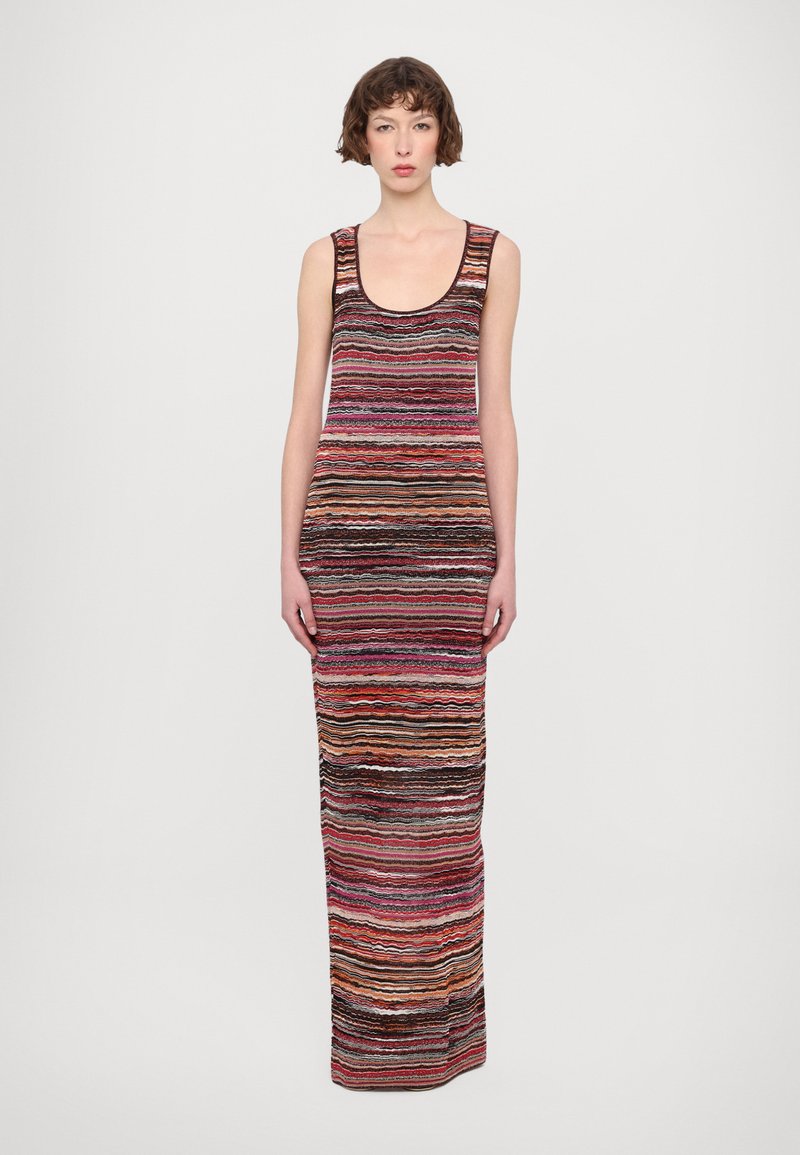 Long, sleeveless dress with a scoop neck, featuring a colorful, wavy striped pattern in shades of red, pink, black, and orange. Knitted texture.
