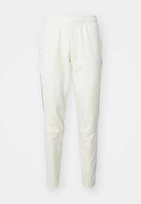 Hellbeige Jogginghose aus strukturiertem Stoff, mit elastischem Bund und Seitentaschen. Schmal zulaufende Beine mit glatter Oberfläche.