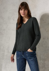 Dunkelgrüner V-Ausschnitt-Pullover aus weichem Strickmaterial, mit langen Ärmeln, gerippten Bündchen und einem dezenten vertikalen Nahtdetail.