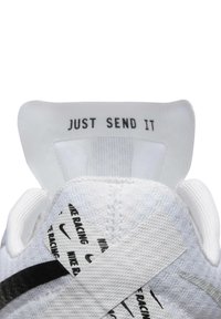 Chaussure de sport blanche avec une empeigne texturée, des bandes d'accent noires et un logo imprimé. La languette du talon affiche le texte "JUST SEND IT" en noir.