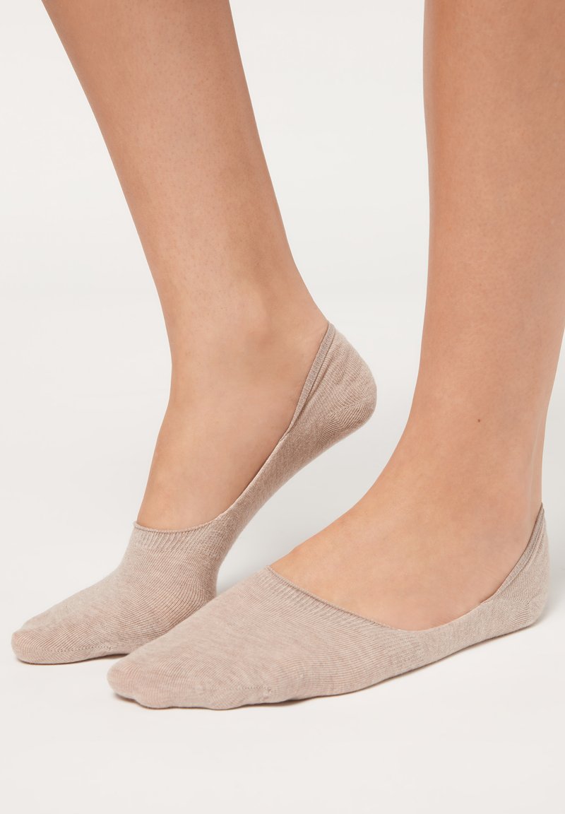 Calzini beige alla caviglia realizzati in morbido tessuto a costine con un design a taglio basso, dotati di una punta senza cuciture e bordi lisci per una vestibilità comoda.