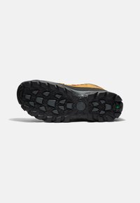 Semelle extérieure en caoutchouc noir avec des crampons profonds, présentant une combinaison de traction robuste et une tige en cuir marron avec des accents gris.