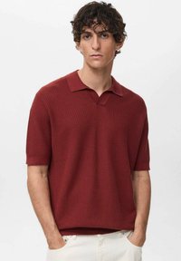 Short-sleeve burgundy polo shirt in textured knit, featuring a V-neck collar and a relaxed fit. Hem is straight with no visible patterns or accents.