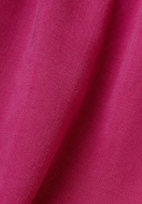 Tissu magenta vif avec une texture de tissage fin visible et des plis subtils créant des ombres douces et des reflets.