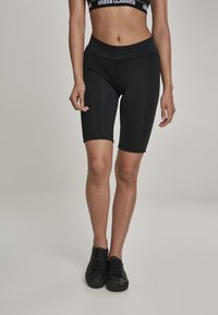 Svarta högmidjade cykelbyxor i ett stretchigt material, med en sömlös design som når midjan på låret. Matchas med svarta sneakers.