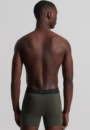 Boxers verts olive avec une taille noire ornée de la marque "SUPERDRY". Texture lisse, design ajusté. Vue arrière.