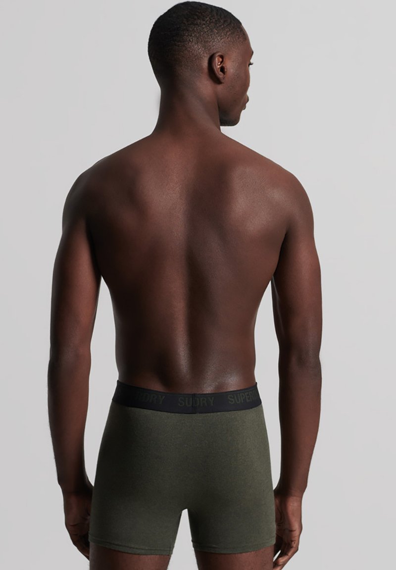 Boxers verts olive avec une taille noire ornée de la marque "SUPERDRY". Texture lisse, design ajusté. Vue arrière.