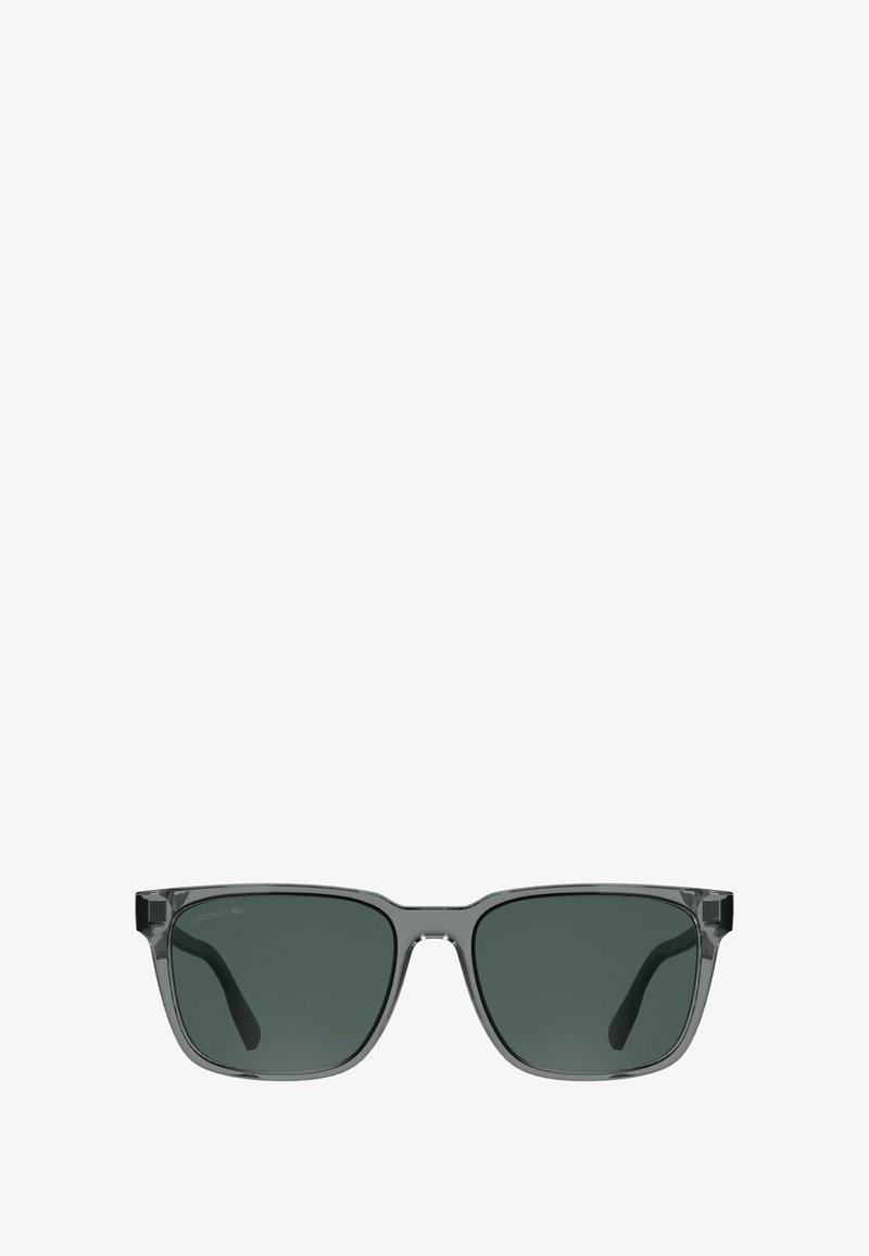 Occhiali da sole grigi con lenti rettangolari, tinta verde scuro e montatura trasparente. Presentano aste spesse e un marchio discreto sul lato.