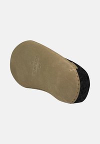 Chaussure en daim beige avec une tige en feutre noir et une semelle douce et texturée. Présente des accents cousus et le logo de la marque sur la base.