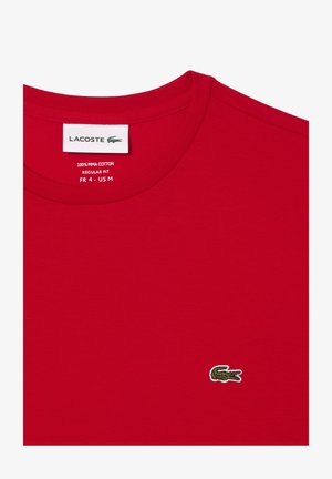 Rotes Pima-Baumwoll-T-Shirt mit Rundhalsausschnitt, mit einem kleinen gestickten Lacoste-Krokodil-Logo in Grün und Weiß auf der linken Brust.